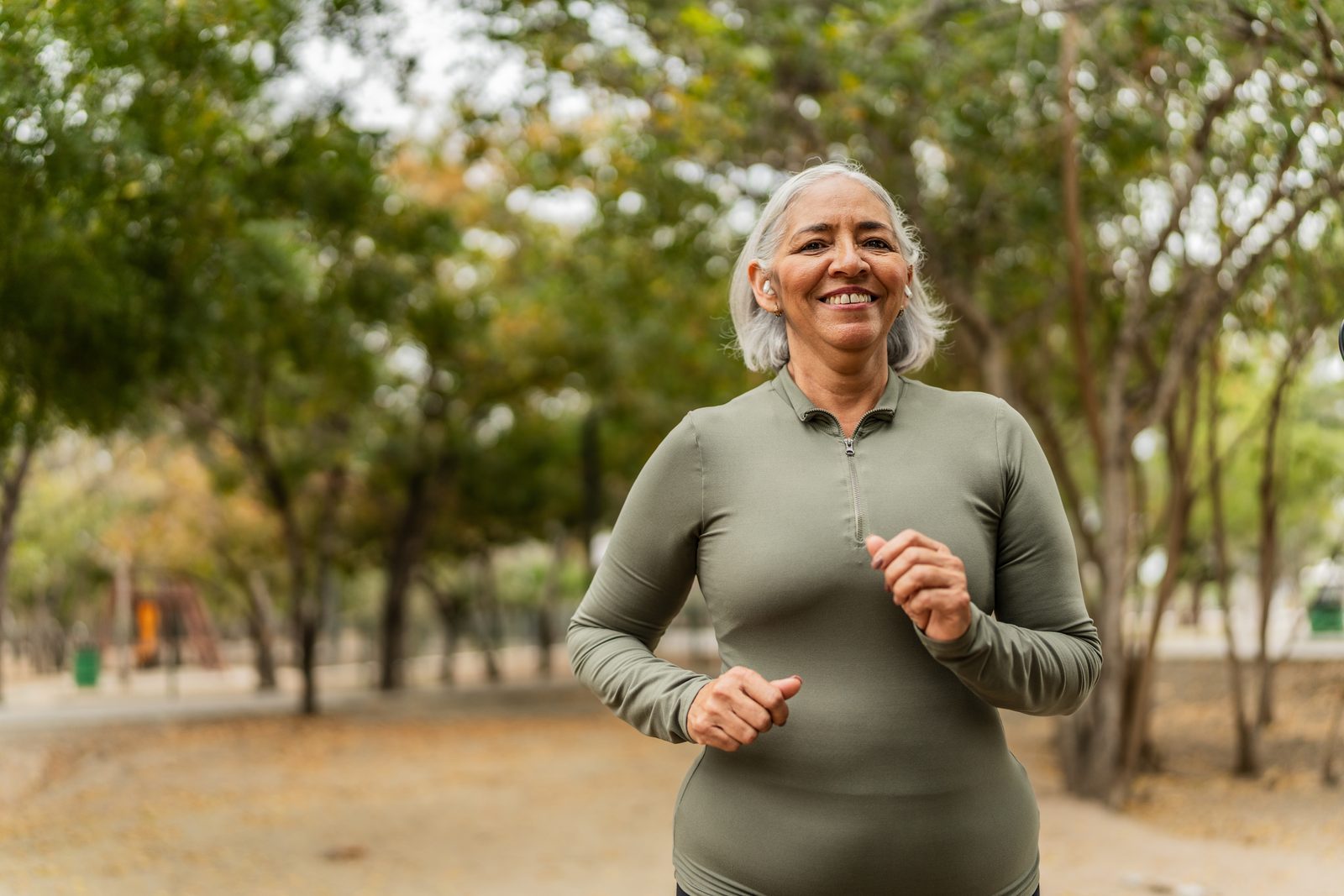 A woman jogging outdoors with a warm, confident smile